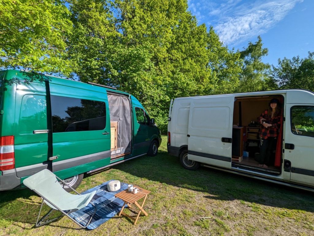 A green an a white van camping next to each other