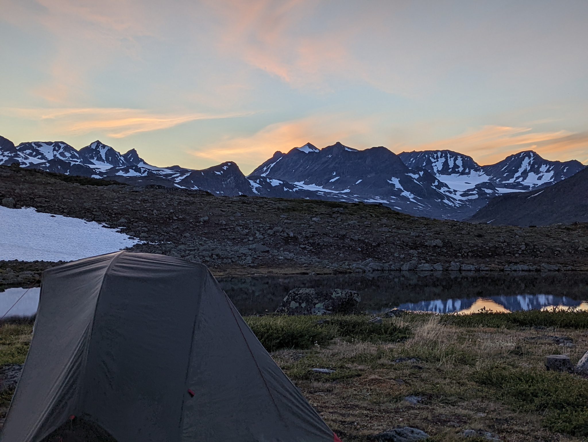 a colorful sunset afterglow in the mountains with a tent in the foreground